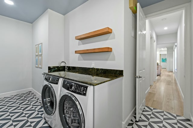 clothes washing area with washing machine and clothes dryer and light wood-type flooring