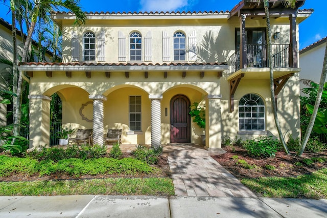 mediterranean / spanish house featuring stucco siding, a balcony, and a porch