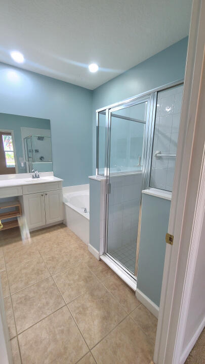 bathroom featuring plus walk in shower, tile patterned flooring, and vanity