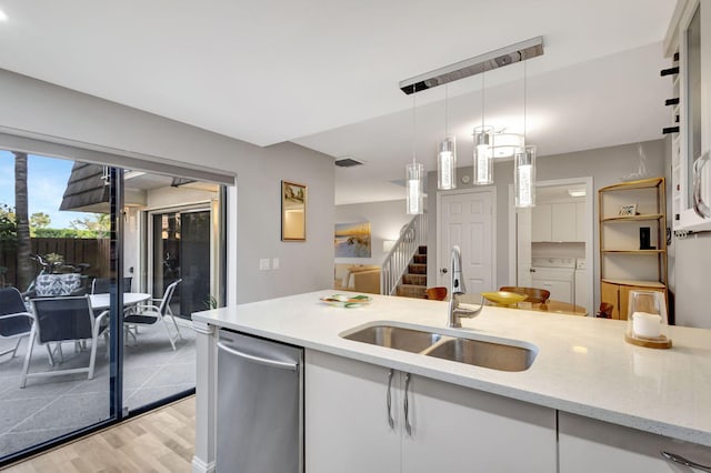 kitchen with pendant lighting, white cabinets, sink, separate washer and dryer, and light stone counters