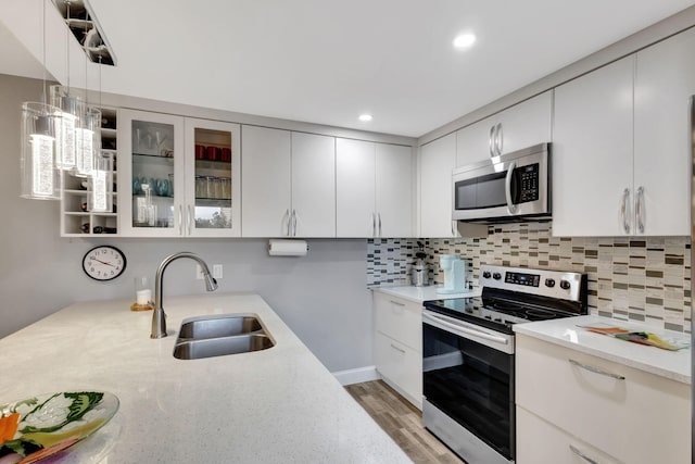 kitchen featuring appliances with stainless steel finishes, white cabinetry, pendant lighting, and sink