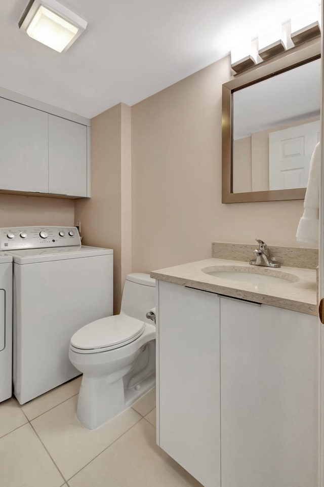 bathroom with vanity, washing machine and dryer, tile patterned floors, and toilet