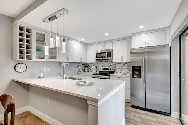 kitchen with sink, white cabinetry, stainless steel appliances, and hanging light fixtures