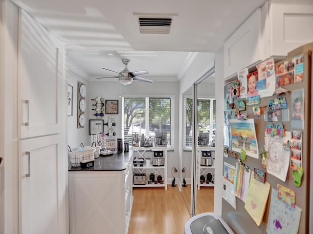 interior space featuring ceiling fan, crown molding, and light hardwood / wood-style floors