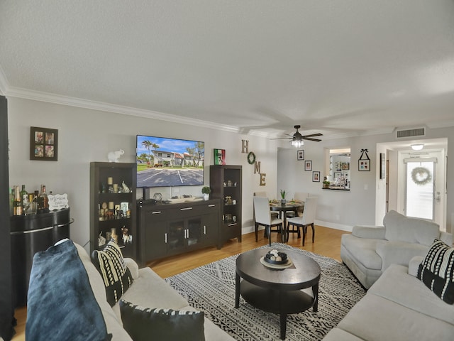 living room featuring ceiling fan, light hardwood / wood-style flooring, a textured ceiling, and ornamental molding