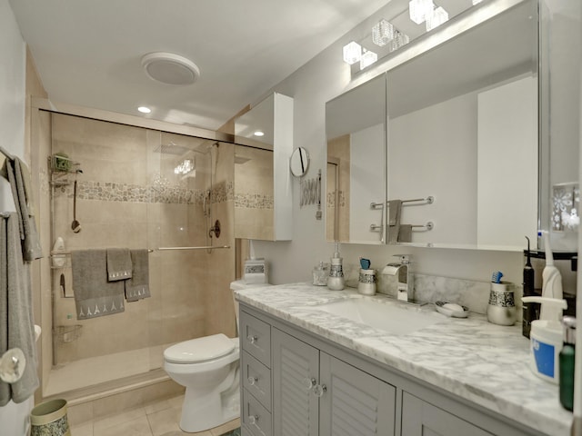 bathroom with tile patterned floors, vanity, toilet, and a shower with door