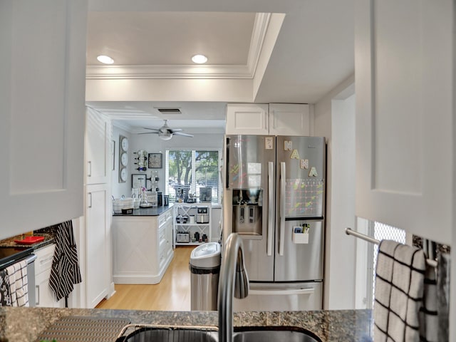 kitchen with ceiling fan, stainless steel fridge, light wood-type flooring, ornamental molding, and white cabinetry