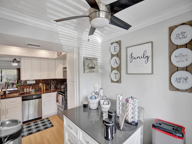 kitchen featuring decorative backsplash, light wood-type flooring, stainless steel appliances, crown molding, and white cabinets