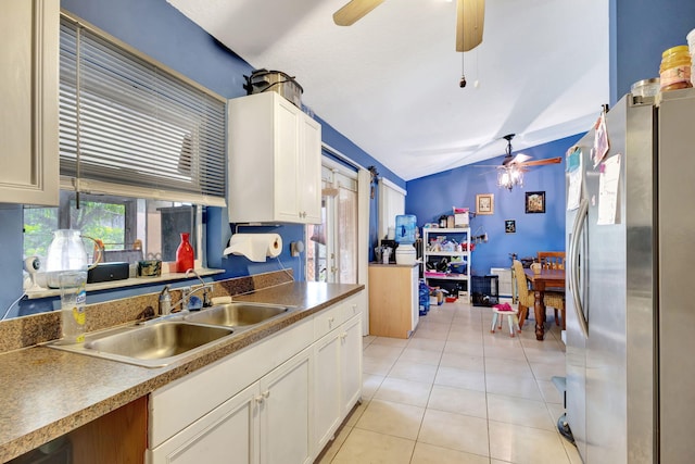 kitchen with stainless steel fridge, sink, white cabinets, lofted ceiling, and light tile patterned flooring