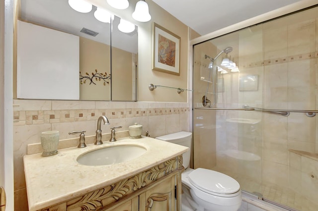 bathroom with vanity, a shower with shower door, tile walls, and toilet