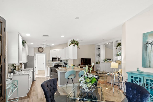 dining room with light hardwood / wood-style flooring, ceiling fan, and sink