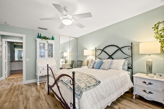 bedroom featuring connected bathroom, light hardwood / wood-style floors, and ceiling fan