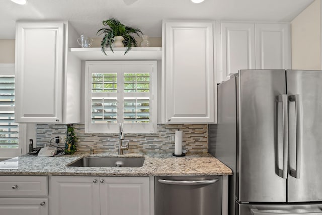 kitchen featuring white cabinets, decorative backsplash, stainless steel appliances, and sink