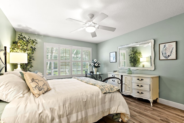 bedroom with ceiling fan, wood-type flooring, and a textured ceiling