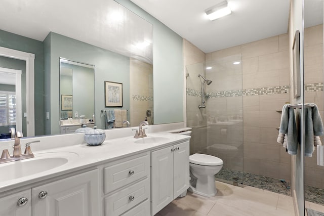 bathroom featuring vanity, toilet, and a tile shower