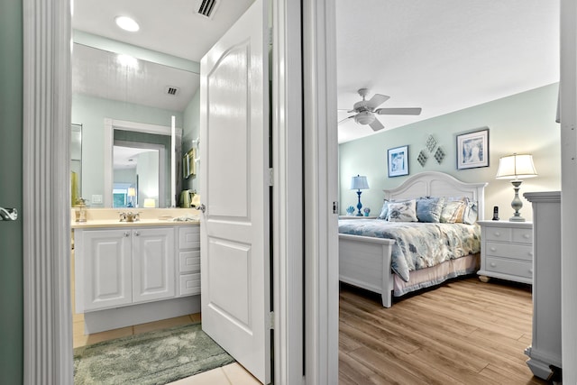 bedroom featuring ceiling fan, sink, connected bathroom, and light hardwood / wood-style flooring