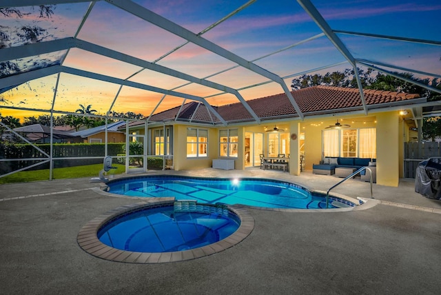 view of pool featuring glass enclosure, an outdoor hangout area, a pool with connected hot tub, a ceiling fan, and a patio area