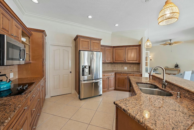 kitchen featuring brown cabinets, light tile patterned floors, stainless steel appliances, a sink, and dark stone counters