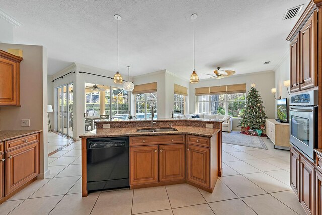 kitchen featuring light stone counters, stainless steel appliances, sink, light tile patterned floors, and decorative light fixtures