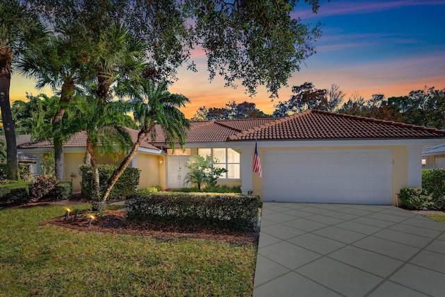 mediterranean / spanish-style house with a tile roof, an attached garage, and stucco siding