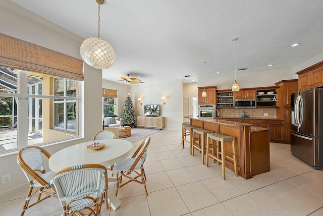 tiled dining room with ceiling fan and crown molding