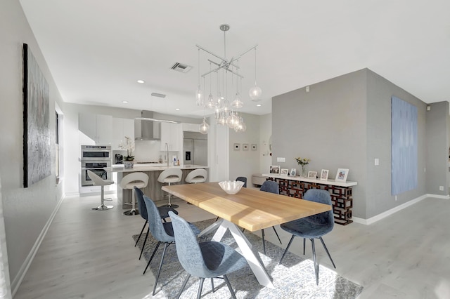 dining space featuring light wood-type flooring and a chandelier