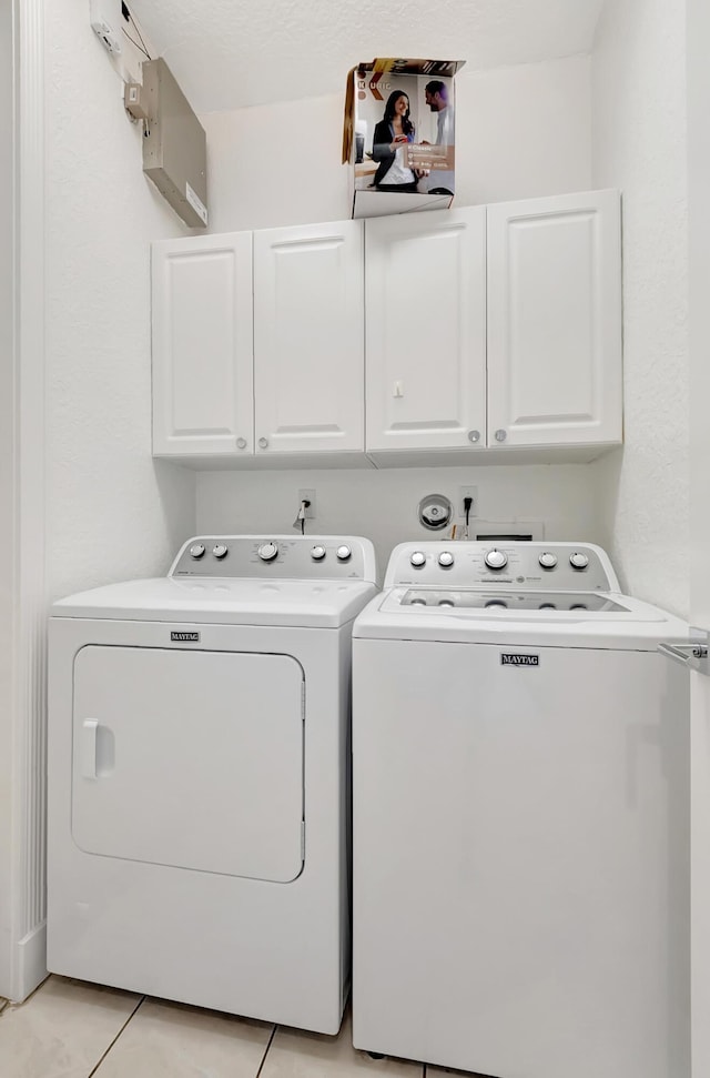 laundry room featuring light tile patterned flooring, cabinets, and washing machine and dryer