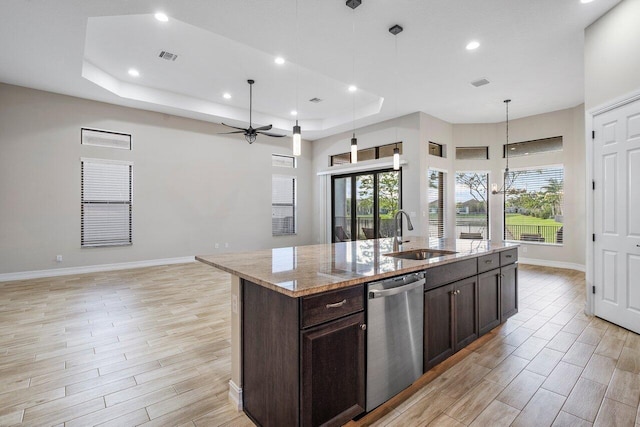 kitchen with dishwasher, a kitchen island with sink, ceiling fan with notable chandelier, sink, and light stone counters