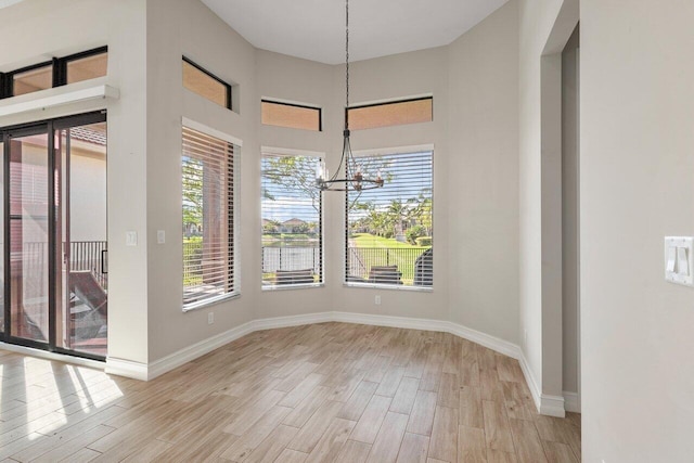 unfurnished dining area with light wood-type flooring and an inviting chandelier