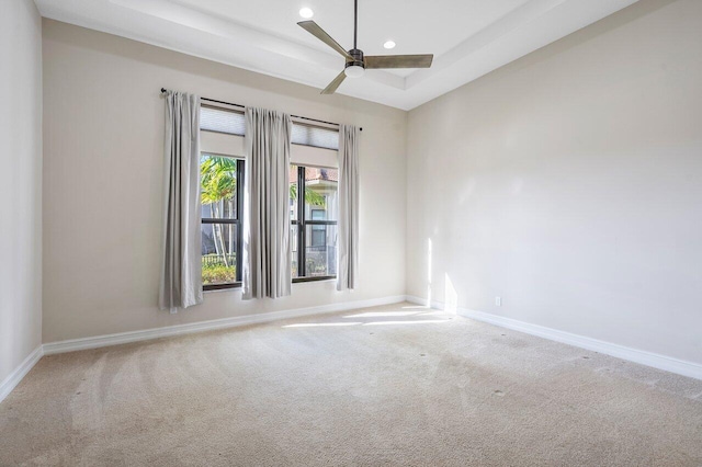 spare room featuring carpet flooring, a raised ceiling, and ceiling fan