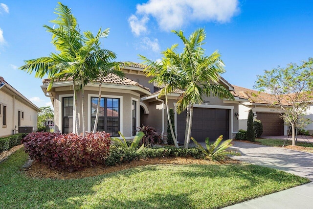 mediterranean / spanish home with a garage, central air condition unit, and a front yard