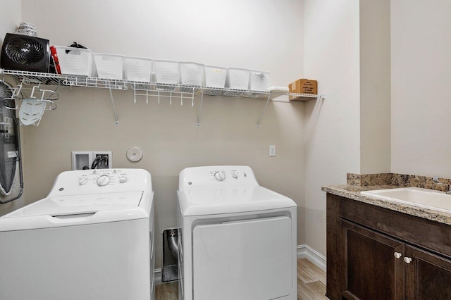 laundry room featuring washer and dryer, cabinets, sink, and light hardwood / wood-style flooring