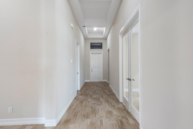 hallway with a raised ceiling and light hardwood / wood-style flooring