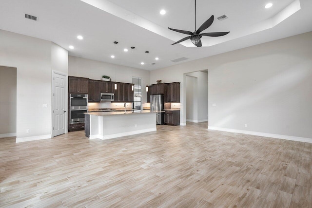 kitchen featuring dark brown cabinetry, stainless steel appliances, ceiling fan, light hardwood / wood-style floors, and an island with sink