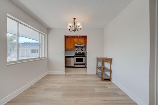 interior space with hanging light fixtures, appliances with stainless steel finishes, tasteful backsplash, light hardwood / wood-style floors, and a chandelier