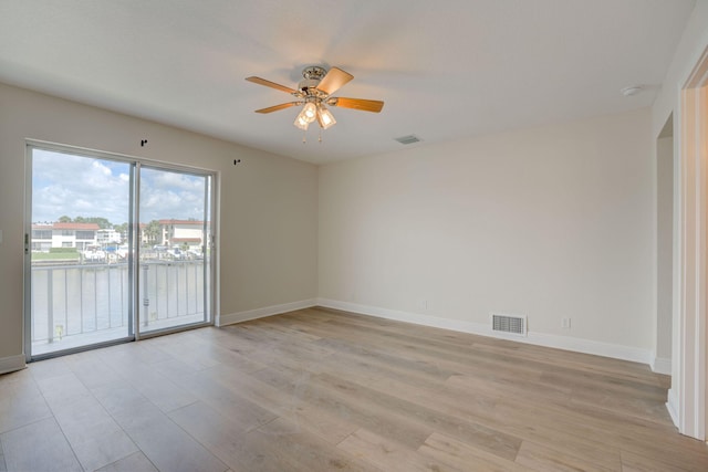 empty room featuring a water view, ceiling fan, and light hardwood / wood-style floors