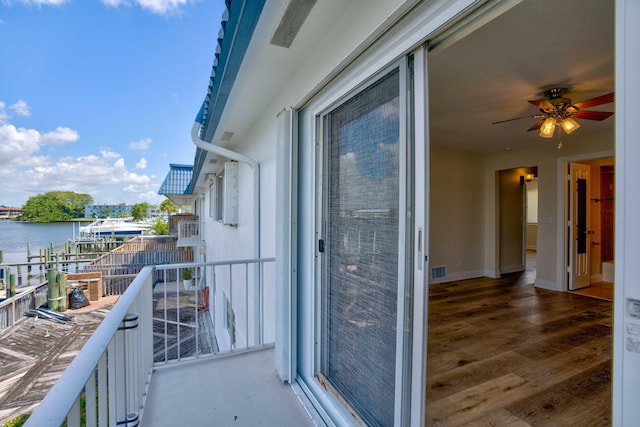 balcony featuring a water view and ceiling fan