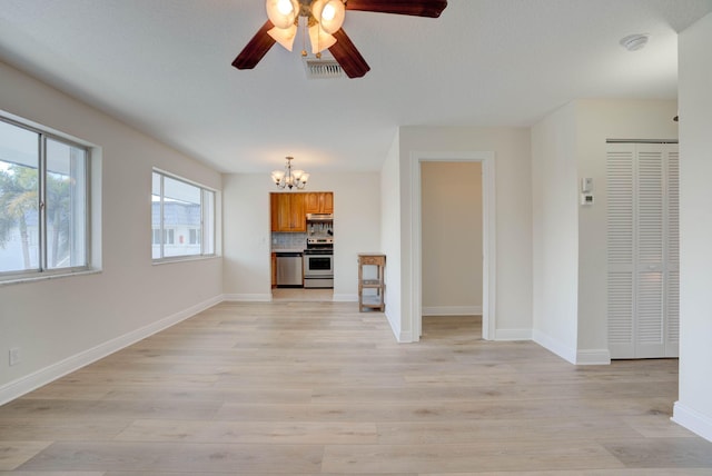 unfurnished living room featuring ceiling fan with notable chandelier and light wood-type flooring