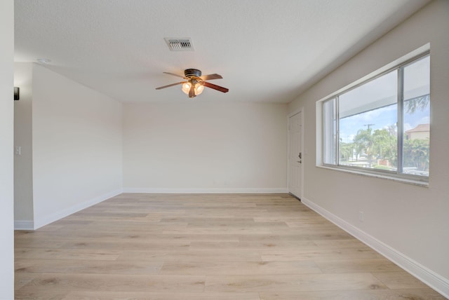 empty room featuring a textured ceiling, light hardwood / wood-style flooring, and ceiling fan