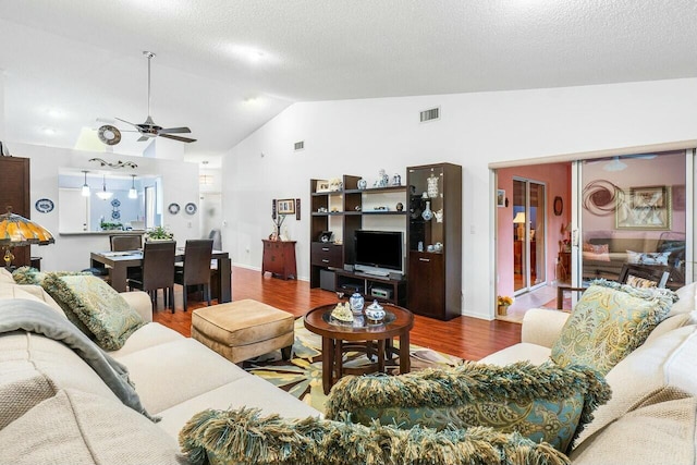 living room with a textured ceiling, hardwood / wood-style flooring, vaulted ceiling, and ceiling fan