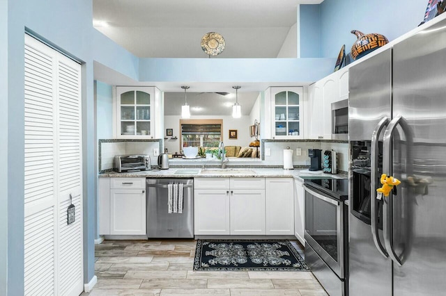 kitchen featuring white cabinets, decorative light fixtures, light stone counters, and appliances with stainless steel finishes