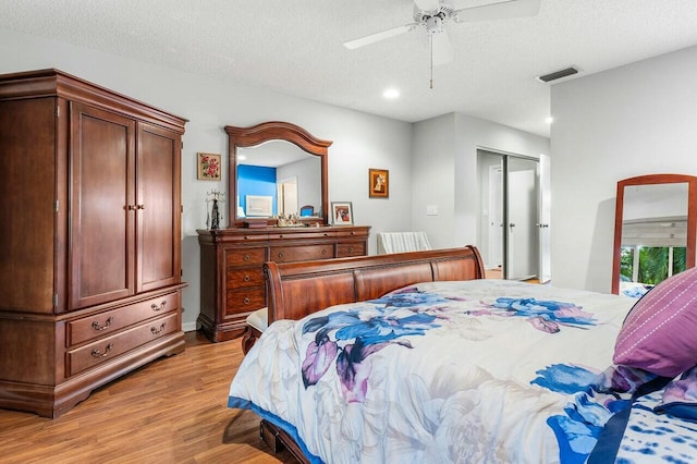 bedroom with ceiling fan, light hardwood / wood-style floors, a textured ceiling, and a closet