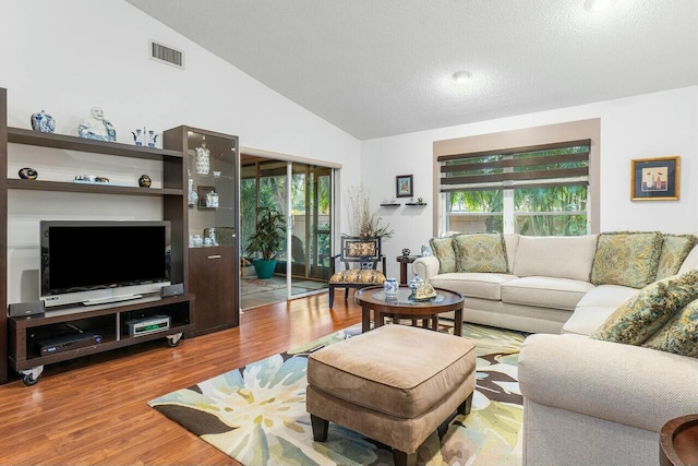 living room featuring a textured ceiling, light hardwood / wood-style floors, and vaulted ceiling