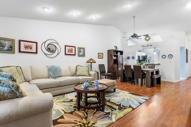 living room featuring light wood-type flooring, a textured ceiling, vaulted ceiling, and ceiling fan