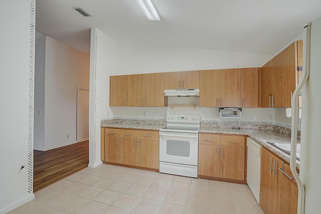 kitchen featuring white appliances, sink, vaulted ceiling, light tile patterned floors, and a textured ceiling