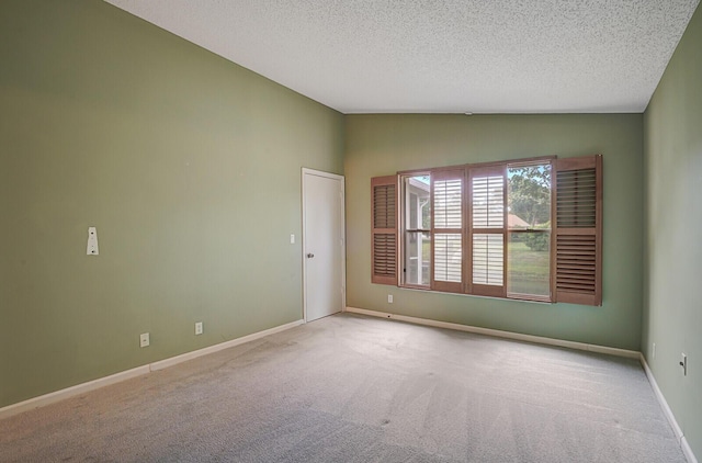 carpeted empty room featuring lofted ceiling and a textured ceiling