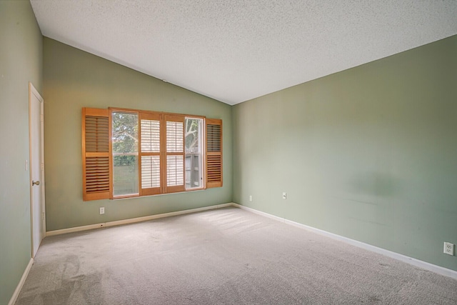 spare room with a textured ceiling, light carpet, and vaulted ceiling