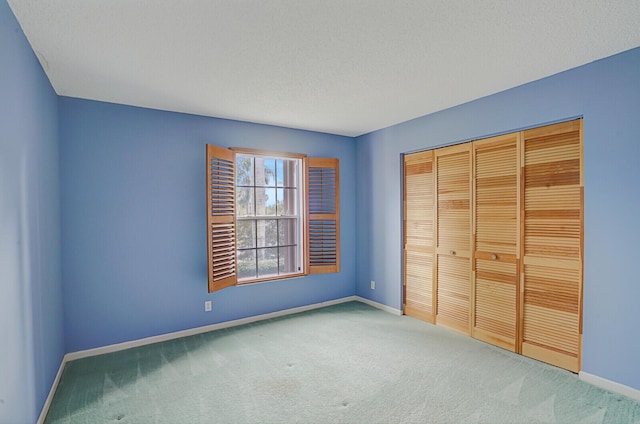 unfurnished bedroom with carpet floors, a textured ceiling, and a closet