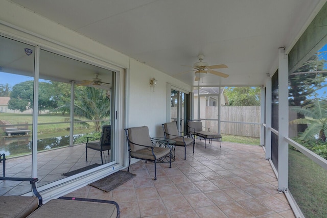 sunroom / solarium with a water view, plenty of natural light, and ceiling fan