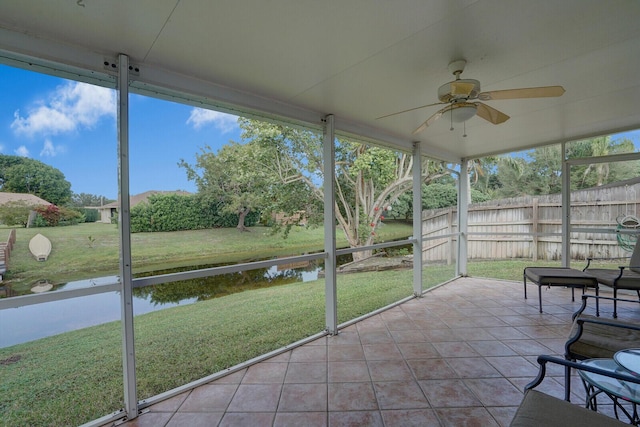 unfurnished sunroom featuring ceiling fan and a water view